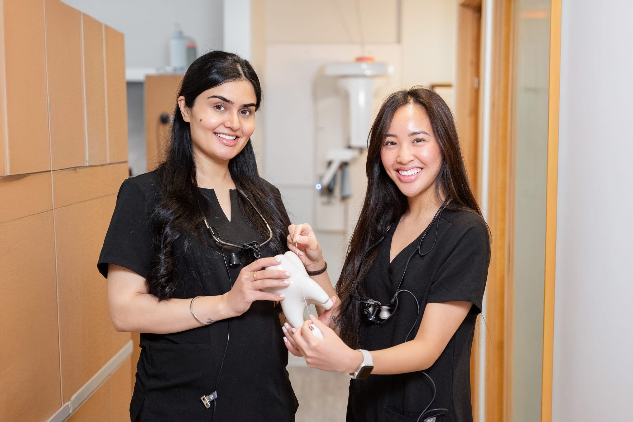 Two Dental Choice team members demonstrating flossing on a tooth model