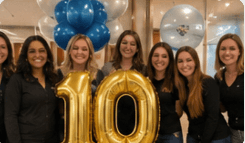 The team holding gold balloons at a clinic anniversary